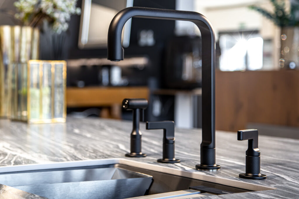 Black faucet with a steel sink in a stylish modern kitchen. Minimalism in refurbished apartment.